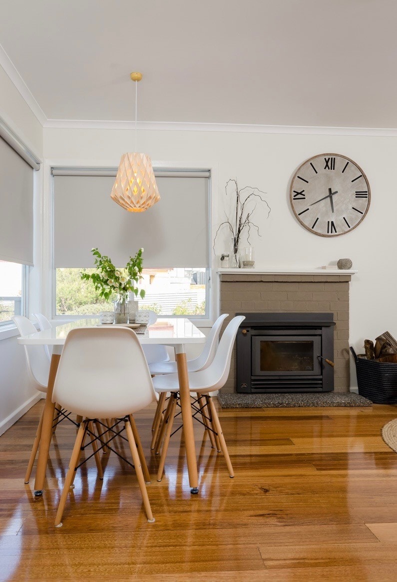 Dining area with Eames chairs, pendant light, wood fireplace and large wall clock