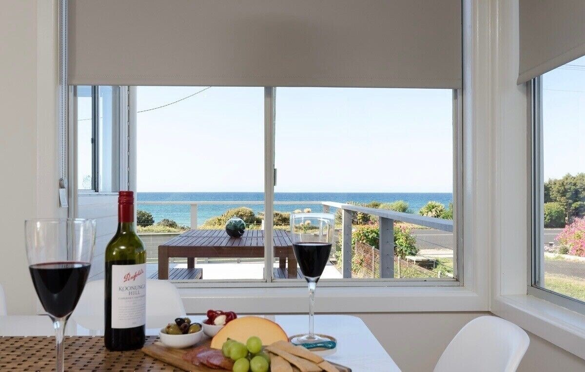 Dining table with wine and cheese board, ocean views through the window