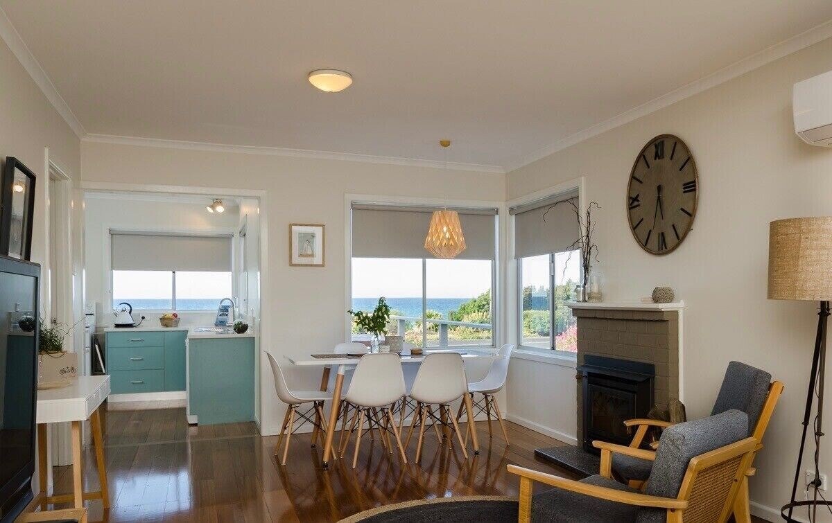 Open plan living and dining with teal kitchen, fireplace and ocean views