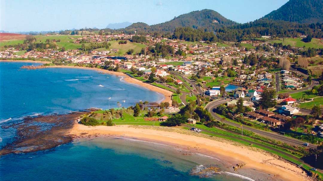 Aerial view of Penguin town showing the bay, beach, foreshore and surrounding hills