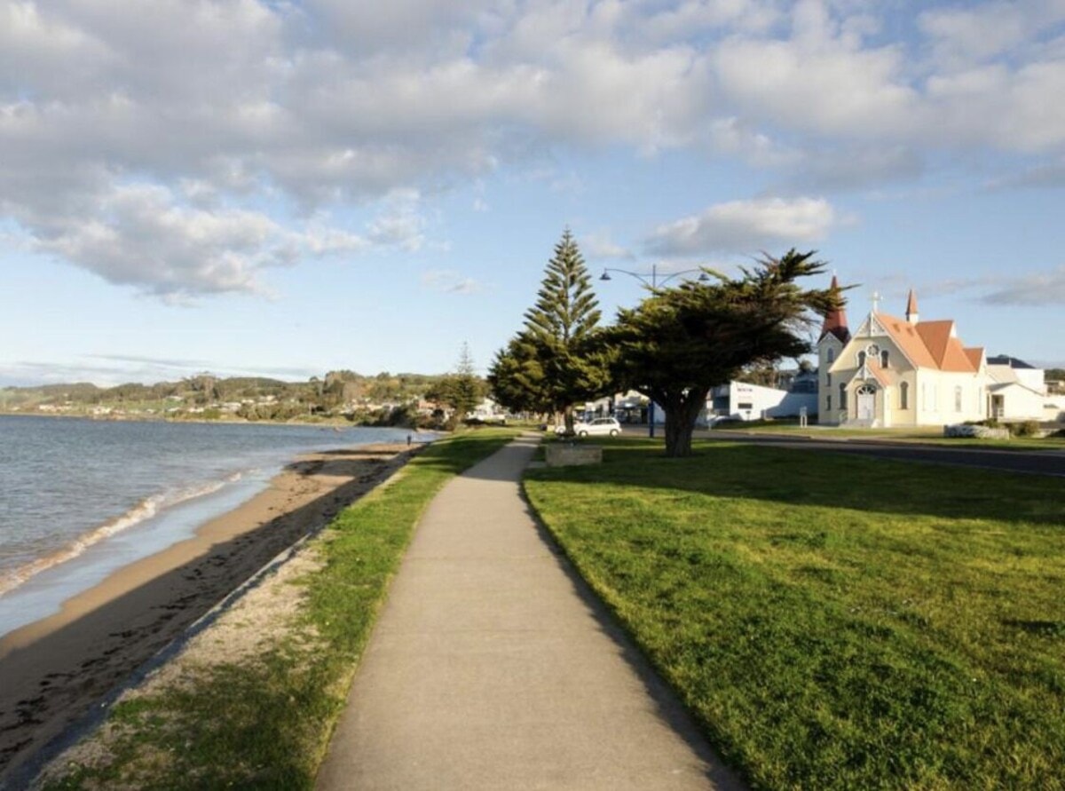 Penguin foreshore walking path alongside the beach with historic church and Norfolk pines