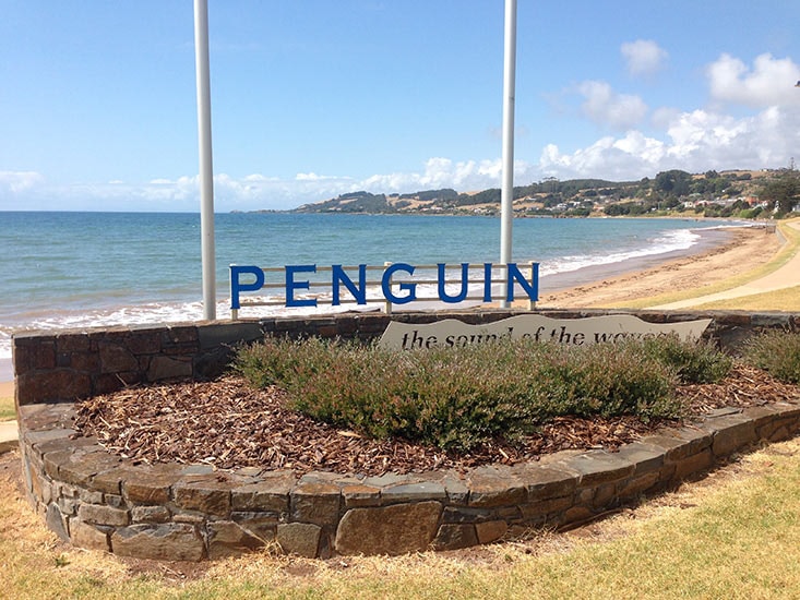 Penguin town sign on the foreshore with beach and rolling hills in the background