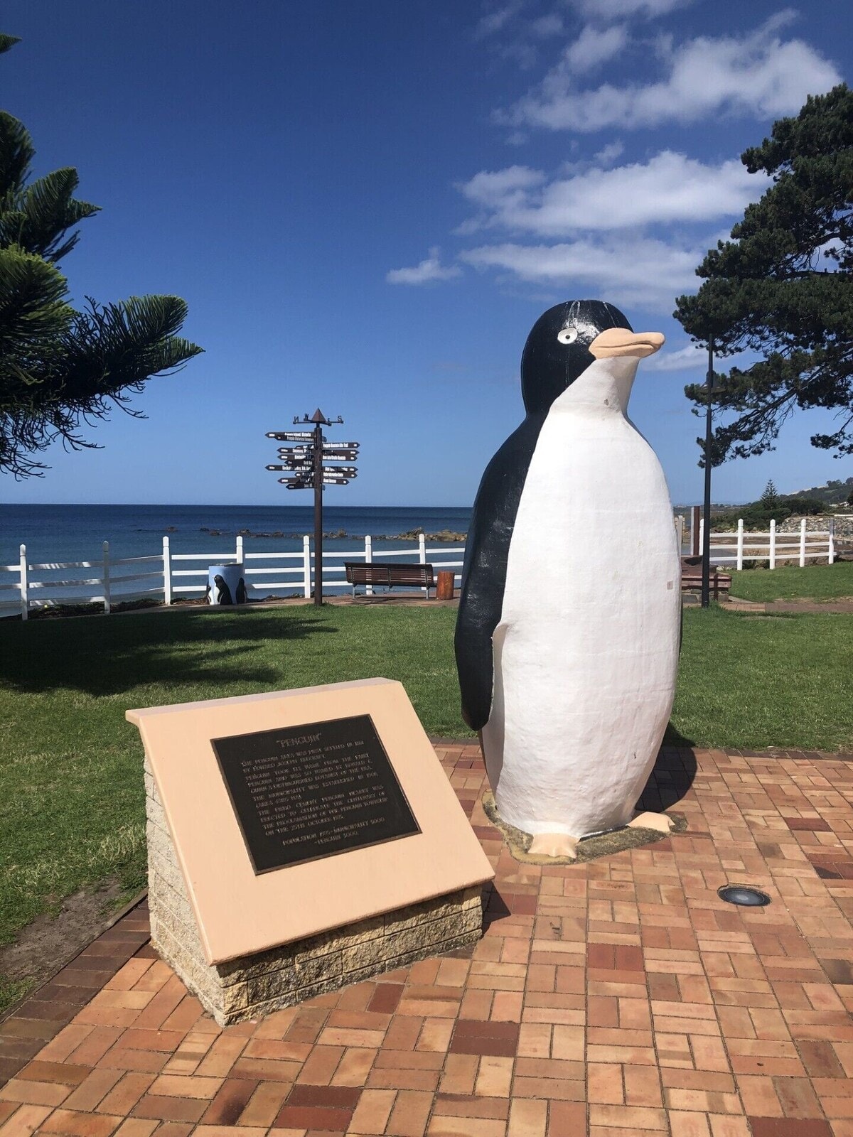 The iconic Big Penguin statue in Penguin town with ocean views and directional signpost