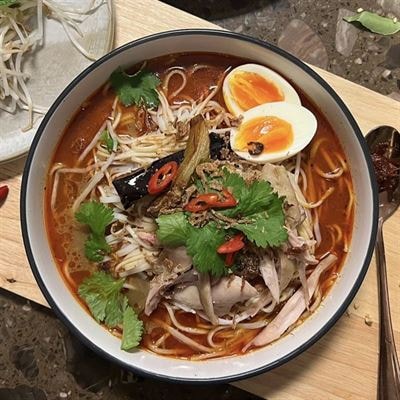 Steaming bowl of Asian noodle soup with soft boiled egg, coriander and chilli at Penguin House restaurant