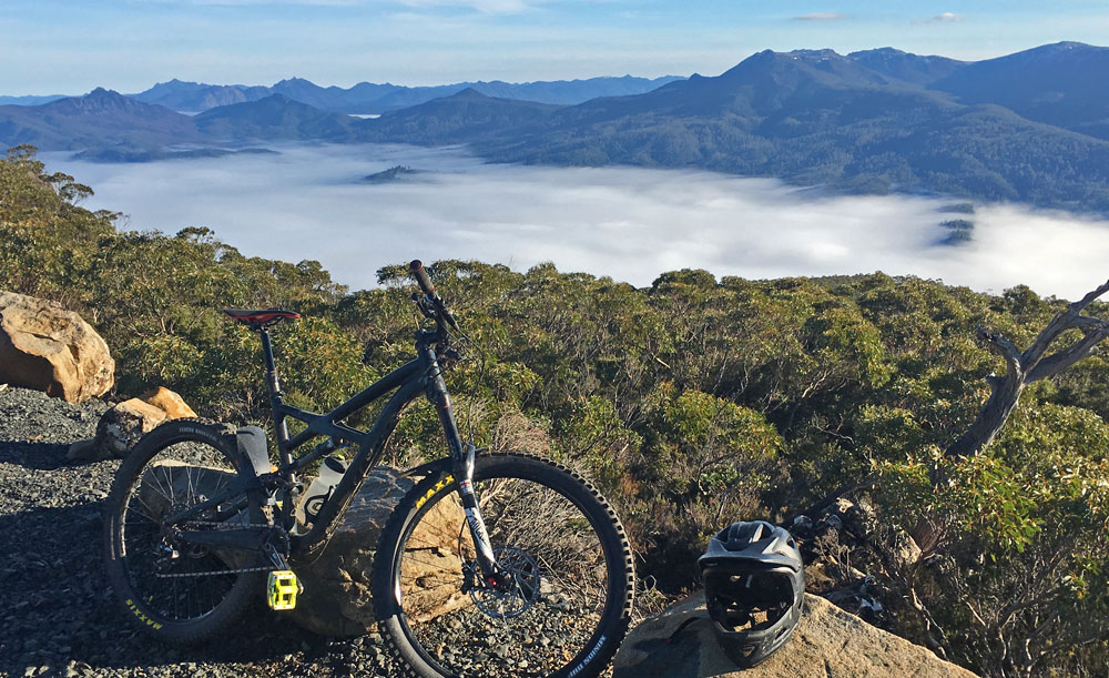 Mountain bike at the summit with cloud-filled valley views in Tasmania